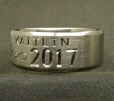 A titanium wedding ring with the name Kaitlin designed by Dave Kessner.