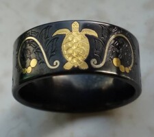 A black zirconium wedding band with a gold inlay turtle designed by Dave Kessner.