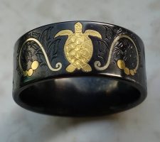 A black zirconium wedding band with a gold inlay turtle designed by Dave Kessner.