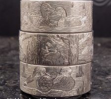 Three stacked rings depicting waterfowl and wildlife